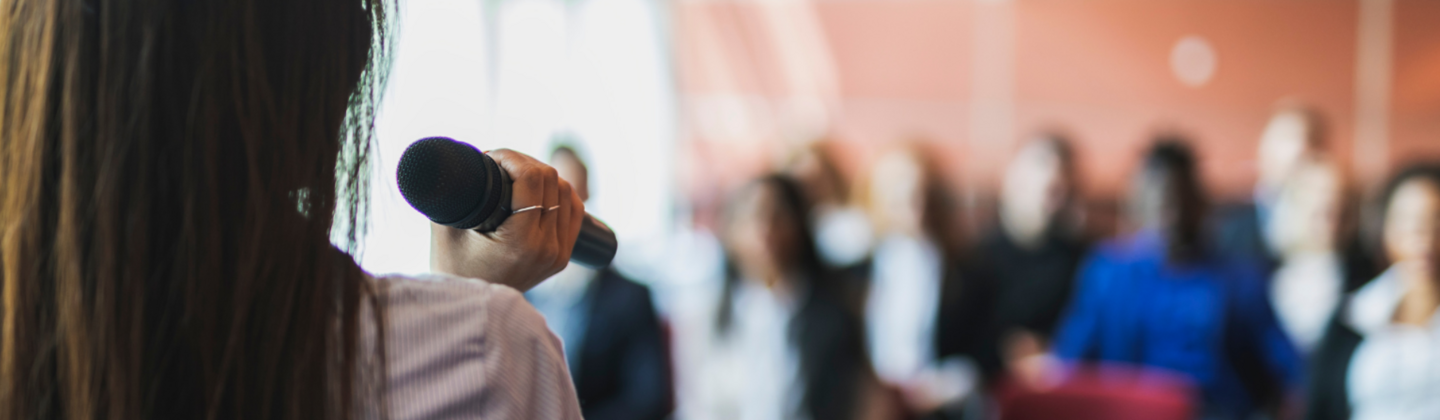 a woman is speaking in front of an audience