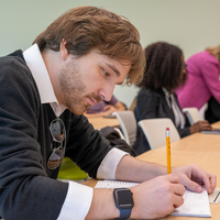 Student leaning over a desk writing something