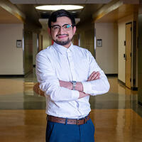 Luis Zelaya standing in campus hallway