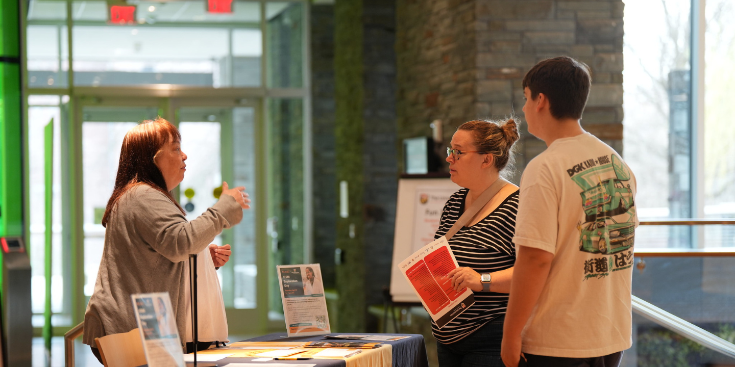 Prospective students talking to program representative at tabling during Open House.