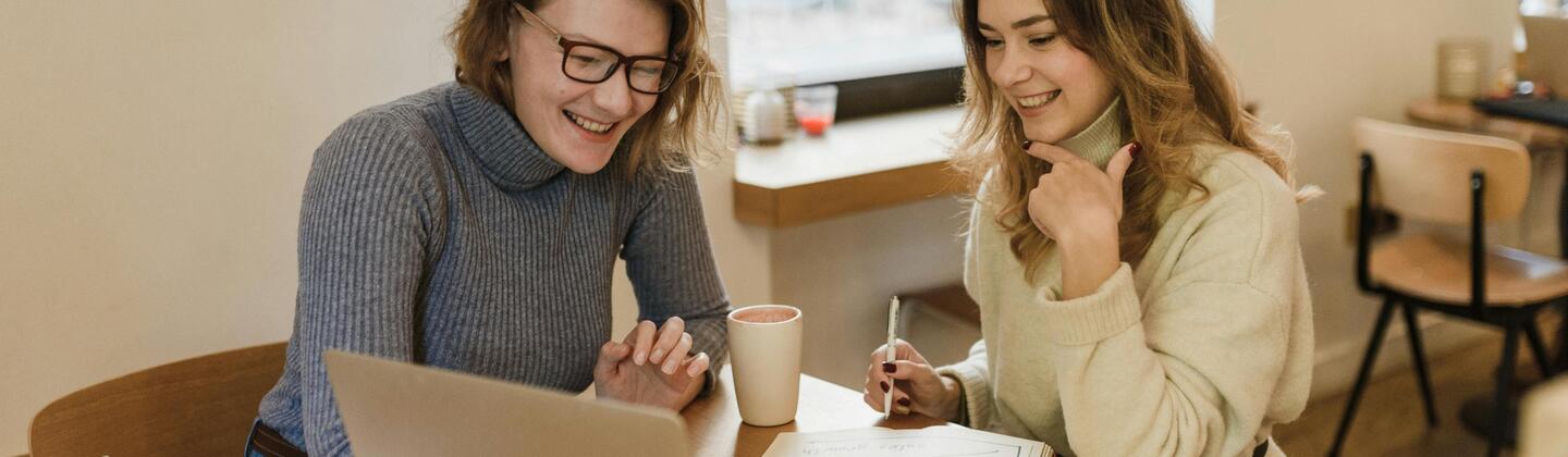 Two people looking at a laptop and talking