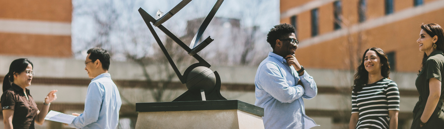 Decorative Image: Students gathered around the sun dial at the center of campus