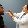 An NP looks in a male patient's throat