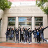 Students in scrubs jumping in front of the UMSON building