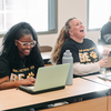 Two students sitting at a desk laughing